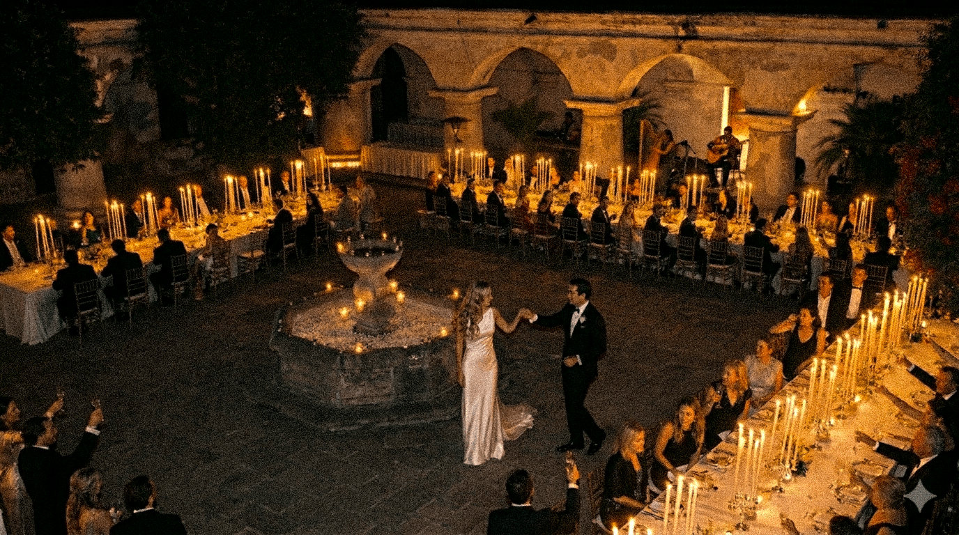 Bride and groom sharing a first dance beside a fountain at a candlelit courtyard wedding