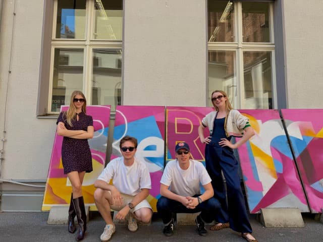 Four of the team outside in Berlin in front of a graffiti sign