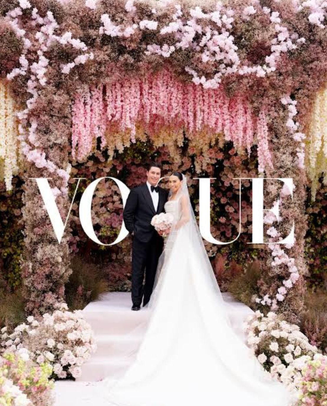 Vogue-featured wedding planned by the Darcy team: couple beneath a pink wisteria floral arch